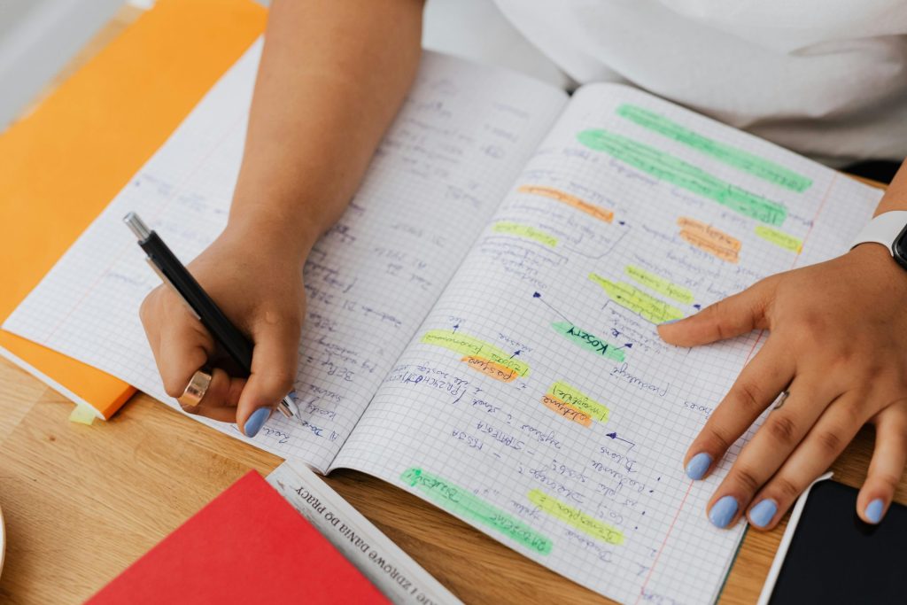 A person writing and highlighting notes in a graph notebook. Ideal for education and productivity themes.